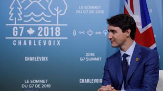 PM Justin Trudeau sits in front of the United Kingdom flag.