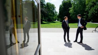 Le président Macron et le PM Trudeau discutent debout sur une terrasse extérieure