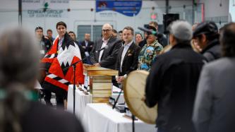 PM Trudeau wears a ceremonial blanket and listens 