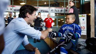 PM Trudeau shakes hands with a young boy in hockey equipment