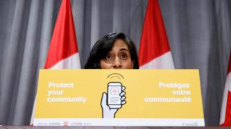 Minister Anand behind a COVID Alert podium card