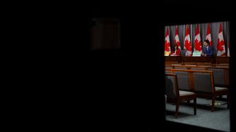 Regard sur le PM Trudeau depuis une porte-fenêtre