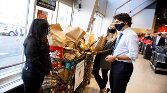 PM Trudeau and two women stand near a food donation bin