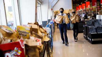 PM Trudeau and a woman walk with grocery bags in hand