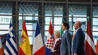 PM Trudeau, Presidents Michel and von der Leyen stand next to a row of national flags