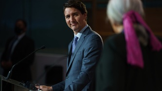 Le premier ministre Justin Trudeau est debout derrière un lutrin et sourit à Mme Mary Simon