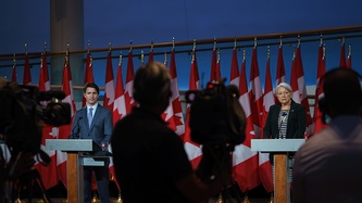Le premier ministre Trudeau et Mme Mary Simon, derrière des lutrins, font face à des techniciens