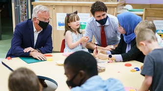 PM Trudeau looks at a woman seated at a table where children play