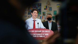 A tunnel view photo of PM Trudeau at a podium through a crowd 