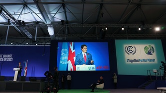 Prime Minister Justin Trudeau at a podium is seen on a large scale screen