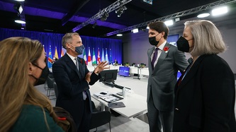 Prime Minister Justin Trudeau and others stand near a man motioning with his hand