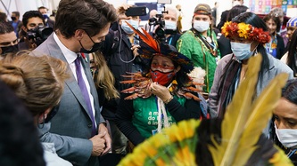 Prime Minister Justin Trudeau looks at a woman among a crowd of people and cameras