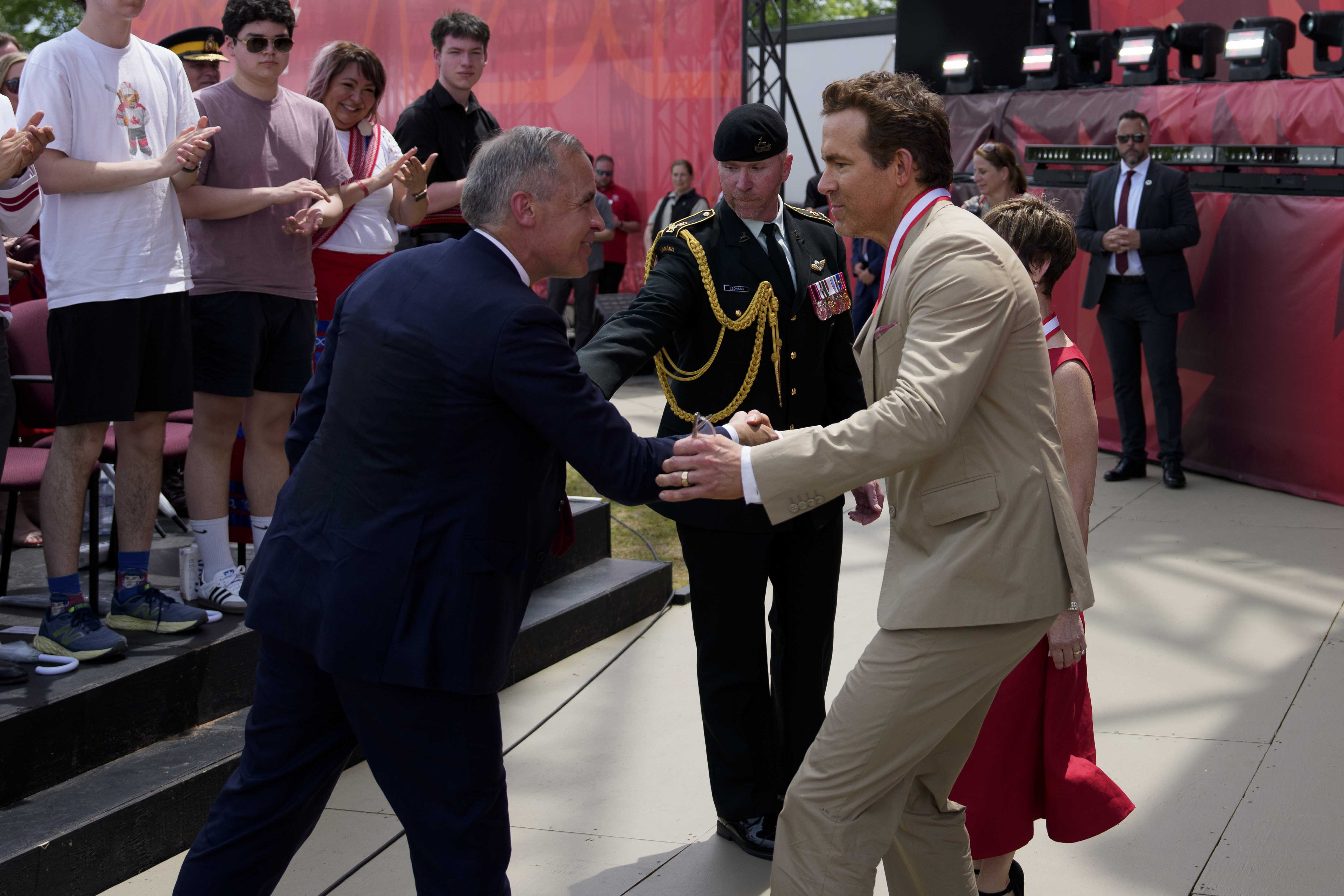 Prime Minister Mark Carney shakes hands with Ryan Reynolds at the national Canada Day ceremony.