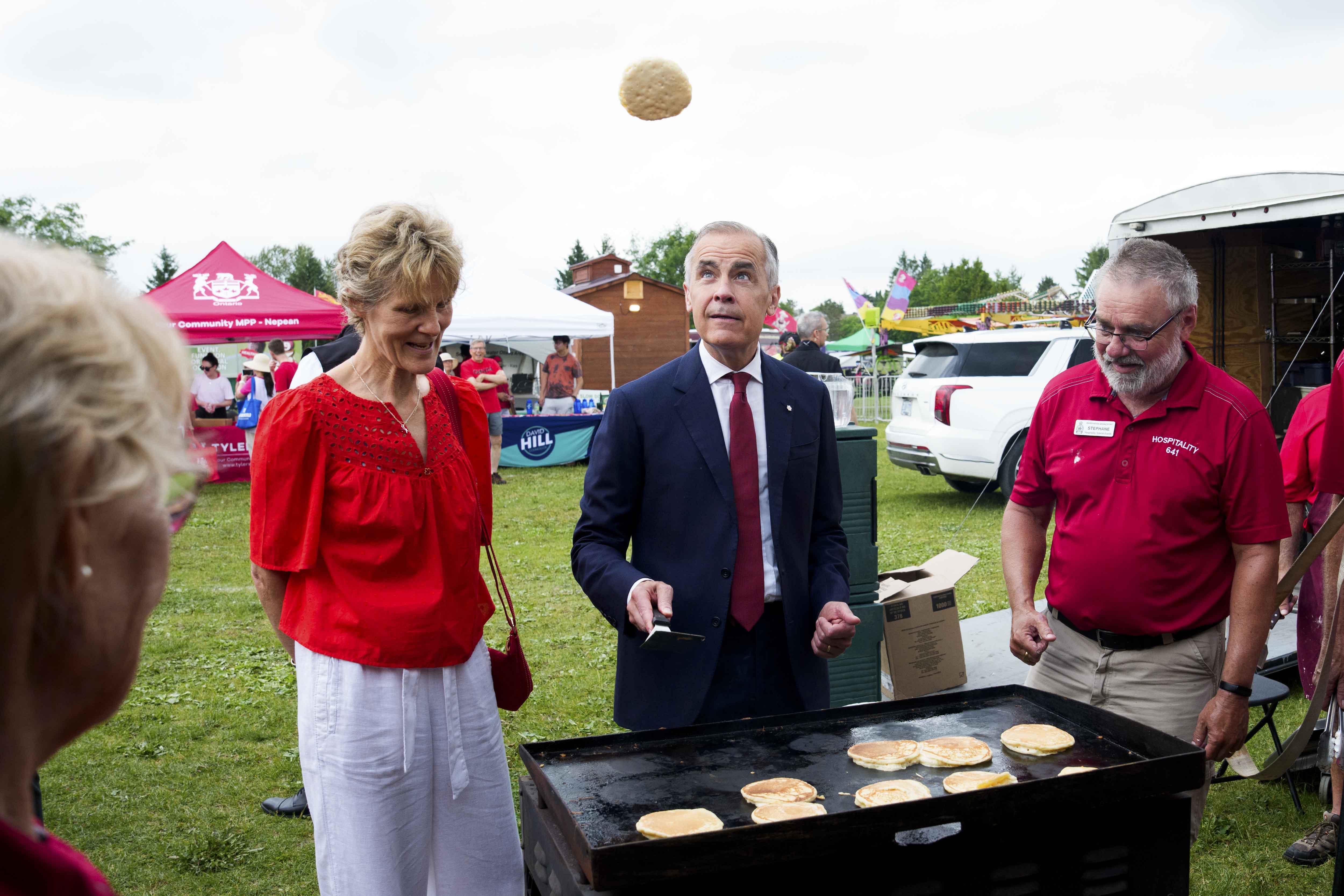 Prime Minister Mark Carney flips pancakes at a Canada Day community breakfast in Barrhaven.
