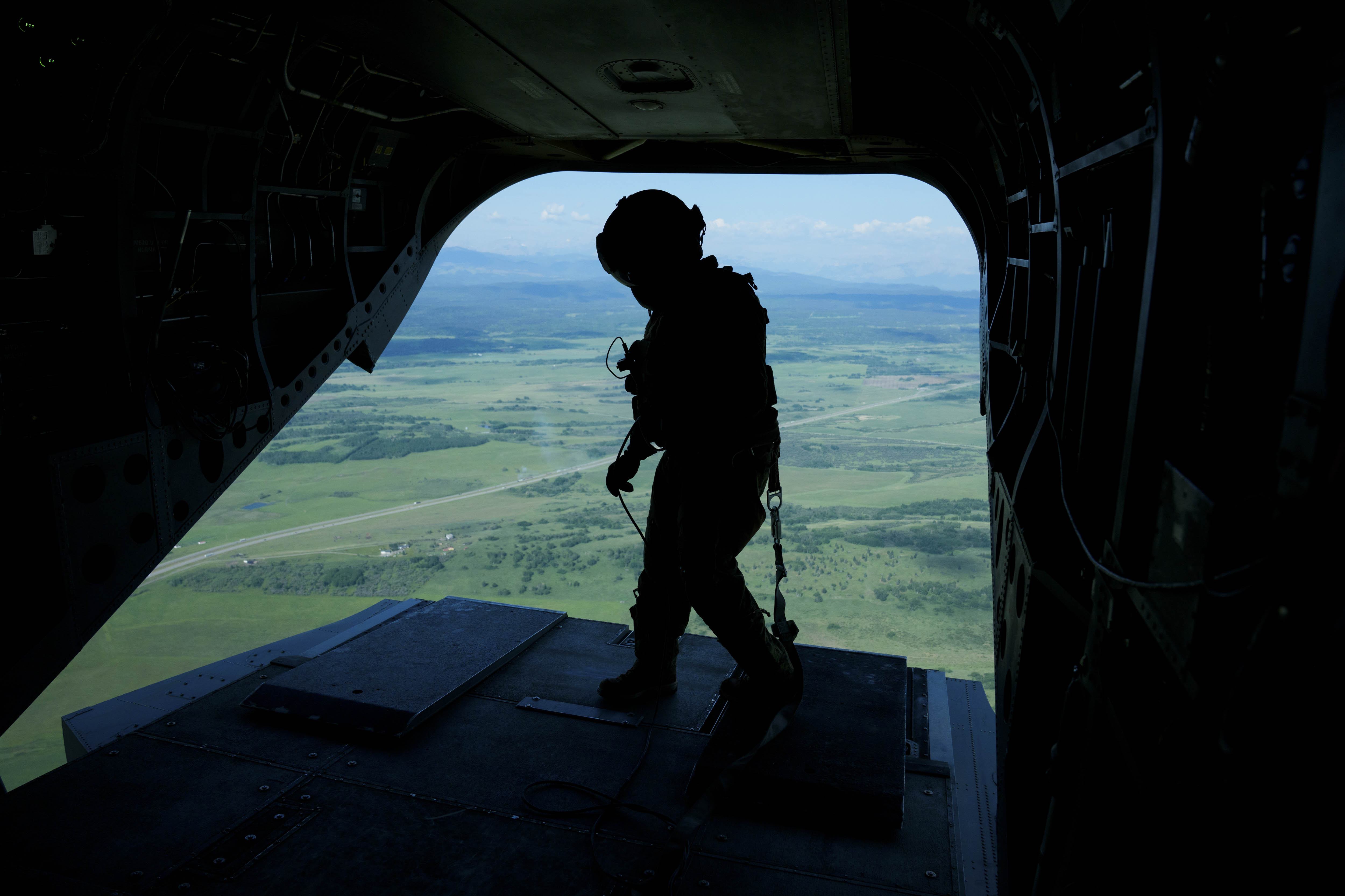 Silhouette d’un membre des FAC debout dans la rampe de chargement ouverte d’un avion de l’Aviation royale canadienne.