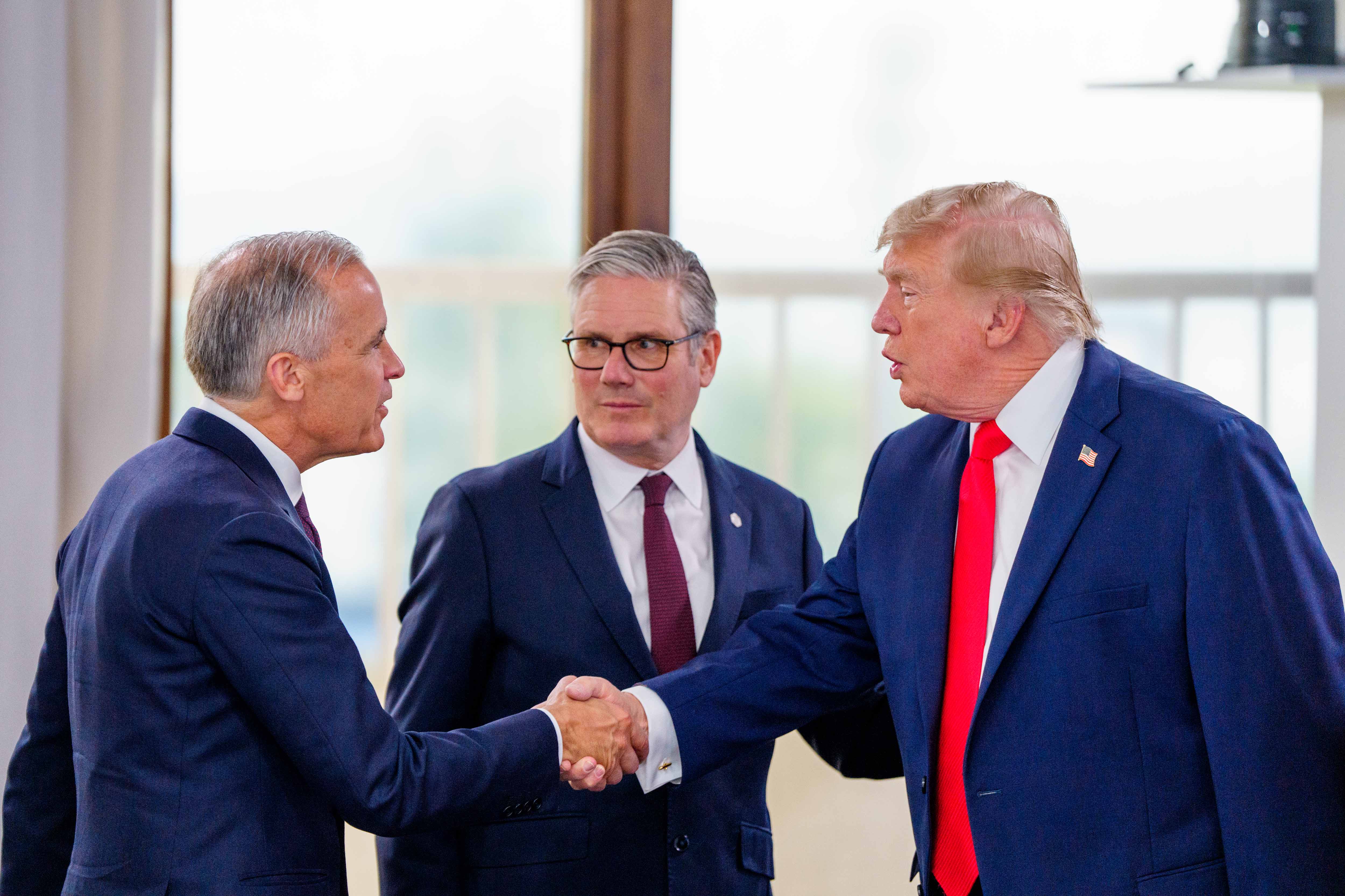 Prime Minister Mark Carney shakes hands with U.S. President Donald J. Trump as British Prime Minister Sir Keir Starmer looks on ahead of the morning G7 Leaders’ Summit working session.