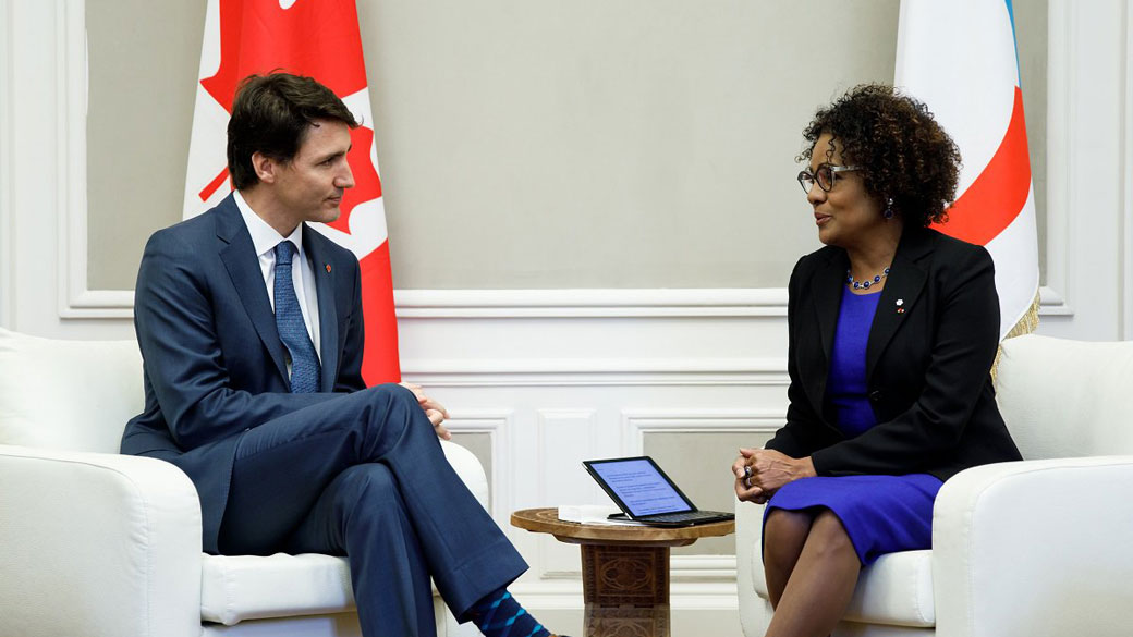 Prime Minister Justin Trudeau and Michaëlle Jean, Secretary-General of the OIF, sit and talk in front of flags representing Canada and the OIF