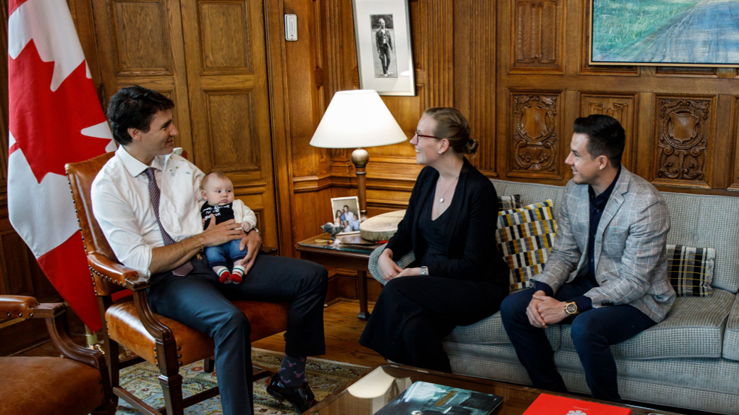 No title Prime Minister Justin Trudeau sits across from Minister Karina Gould and her partner Alberto Gerones holding their baby