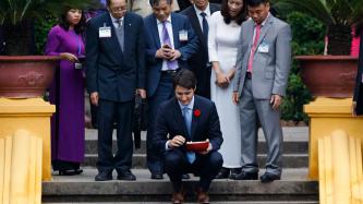 Le premier ministre Justin Trudeau s’agenouille pour nourrir des poissons dans un étang de la maison sur pilotis de Hô Chi Minh sous le regard de représentants vietnamiens