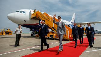 Prime Minister Justin Trudeau waves while walking with a group of Vietnamese officials after getting of an airplane