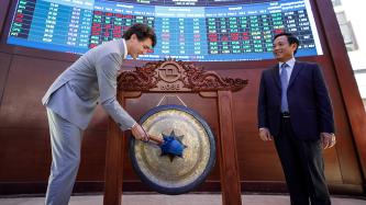 Prime Minister Justin Trudeau symbolically rings the gong at the Ho Chi Minh Stock Exchange, while the Nguyen Vu Quang Trung, chief executive officer of the Ho Chi Minh Stock Exchange, looks on