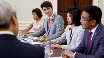 Prime Minister Justin Trudeau and attendees listen to a business leader speak during a meeting