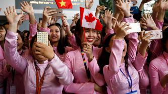 A group of female students holds flags and takes photos on their cell phones