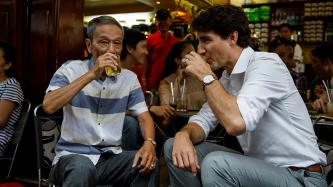 Prime Minister Justin Trudeau sits and drinks coffee with Nguyen Cong Hiep of the Canadian Consulate