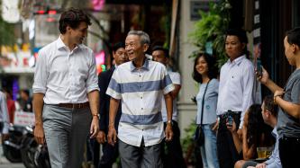 Prime Minister Justin Trudeau walks down the street and talks with Nguyen Cong Hiep of the Canadian Consulate