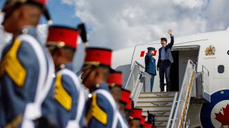  Prime Minister Justin Trudeau stands and waves as he exits the airplane upon his arrival
