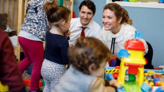 Sophie Grégoire Trudeau smiles while playing with a young girl while Prime Minister Justin Trudeau looks on