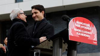 Prime Minister Justin Trudeau embraces MP Adam Vaughan as he steps towards the microphone