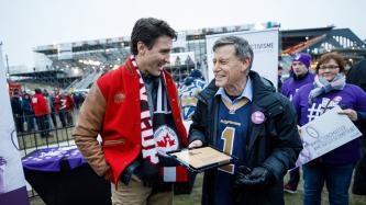 Prime Minister Justin Trudeau speaks with a fan before the Grey Cup