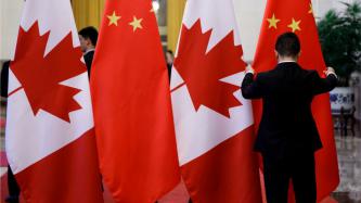 Un préposé place les drapeaux canadiens et chinois