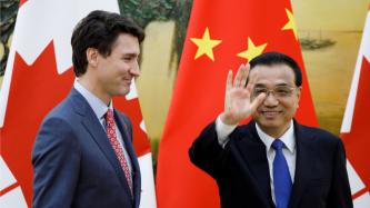 Le premier ministre Li Keqiang salue la caméra sous le regard du premier ministre Justin Trudeau