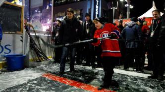 Xavier Trudeau shoots a hockey puck while Prime Minister Justin Trudeau watches