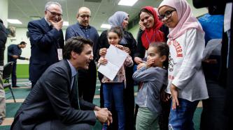 Le premier ministre Justin Trudeau s'accroupit pour parler à une fillette, sous les regards de la famille au Centre culturel islamique de Québec.