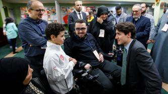 Le premier ministre Justin Trudeau s'agenouille pour parler à un garçon, sous les regards de la famille au Centre culturel islamique de Québec.