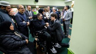 Le premier ministre Justin Trudeau s'agenouille et tient la main d'une victime de la fusillade survenue au Centre culturel islamique de Québec, Aymen Derbali, qui est confiné à un fauteuil roulant.