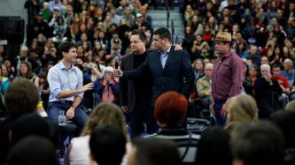A man gives the microphone to PM Trudeau