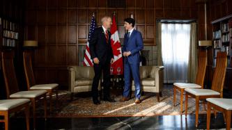 PM Trudeau and Governor Rauner stand and speak with one another
