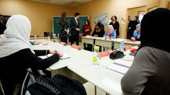 Prime Minister Justin Trudeau speaks to Nahid Aboumansour, director general of Les Petites-Mains, in a boardroom filled with female programme participants