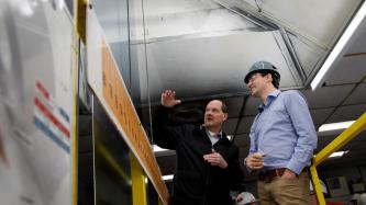 At the ArcelorMittal Dofasco plant, an employee speaks to Prime Minister Justin Trudeau, who is wearing a hard hat and smiling