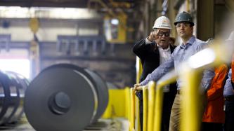 Through safety goggles, Prime Minister Justin Trudeau looks in the direction employee Sean Donnelly is pointing at the ArcelorMittal Dofasco plant