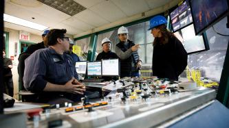 Prime Minister Justin Trudeau points to something during a conversation in the control room of Algoma’s Direct Strip Production Complex alongside MP Terry Sheehan and several steel workers
