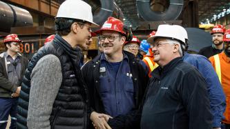 Prime Minister Justin Trudeau talks to a smiling steel worker shaking hands with MP Terry Sheehan at Algoma’s Direct Strip Production Complex