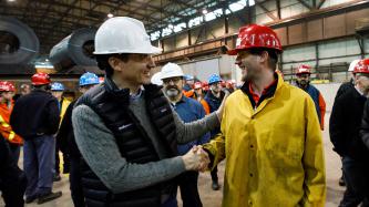 Prime Minister Justin Trudeau shakes hands with a smiling steel worker at Algoma’s Direct Strip Production Complex