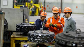 An employee gestures to the mechanics of the EVRAZ Regina facility in conversation with Prime Minister Justin Trudeau and Minister Ralph Goodale