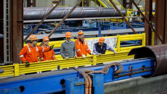 Prime Minister Justin Trudeau and Minister Ralph Goodale wear hard hats and safety goggles as they tour the EVRAZ Regina facility with three uniformed employees