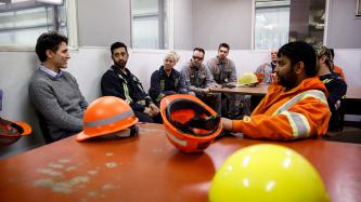 Prime Minister Justin Trudeau sits and talks with a group of eight EVRAZ Regina employees in the break room